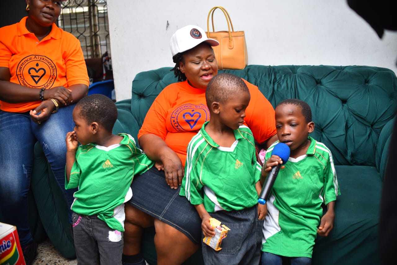 Children in green uniforms standing beside a LAOF volunteer