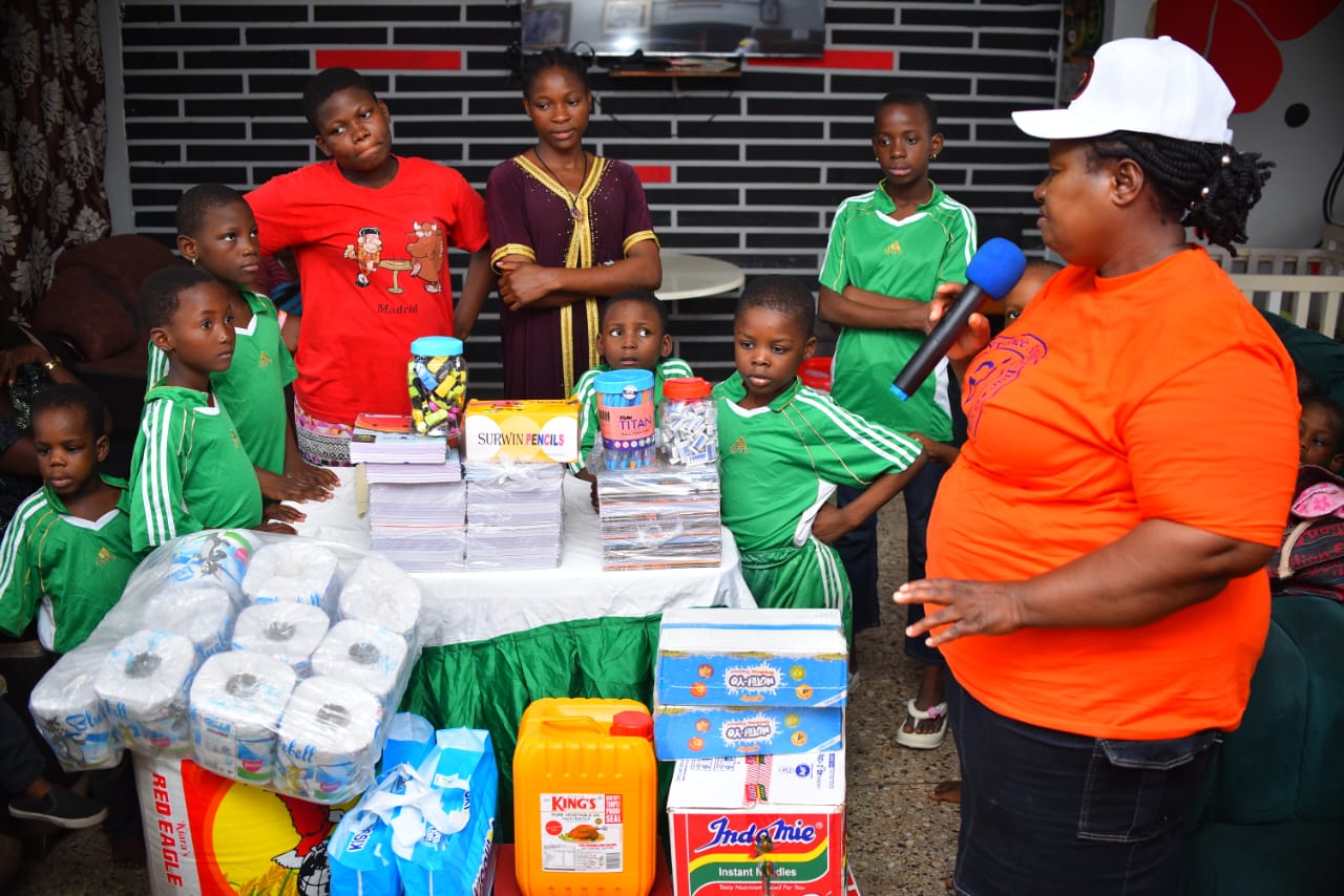 LAOF volunteers and children in green uniforms gathered around supplies